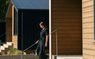 Woman walking away from a timber clad cabin.