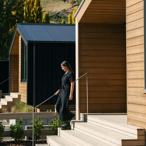 Woman walking away from a timber clad cabin.