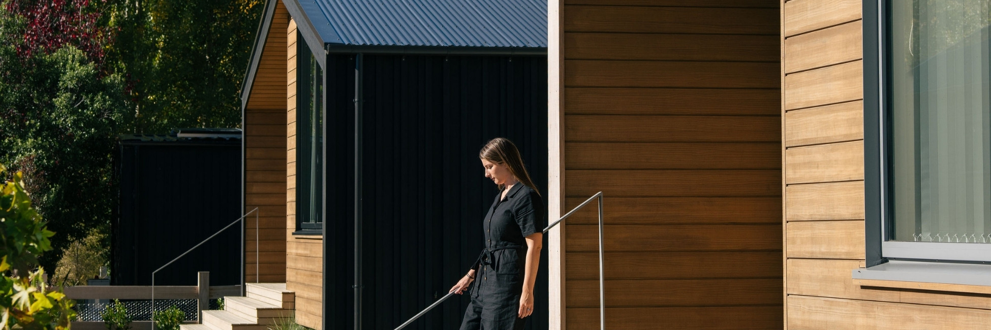 A woman walking down steps away from a building clad in Abodo Vulcan timber.