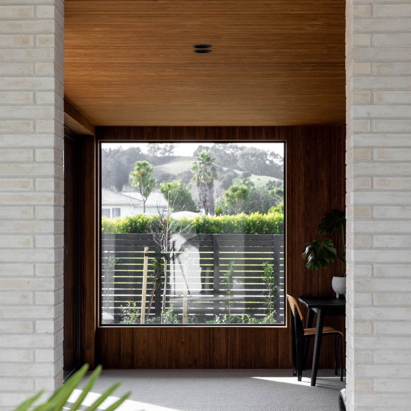 Interior timber cladding on wall and ceiling surround large window.