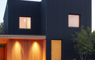 Blackwood house finished in Black ThermoWood® Pine and Organowood treated Larch cladding, photographed at dusk.