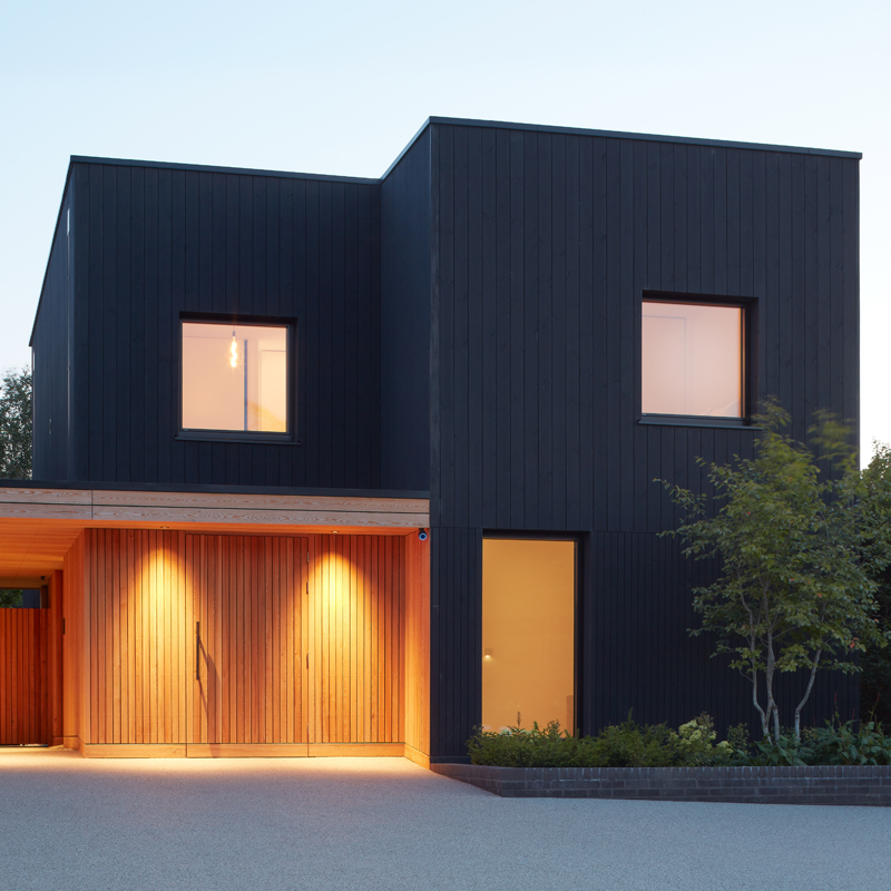 Blackwood house finished in Black ThermoWood® Pine and Organowood treated Larch cladding, photographed at dusk.
